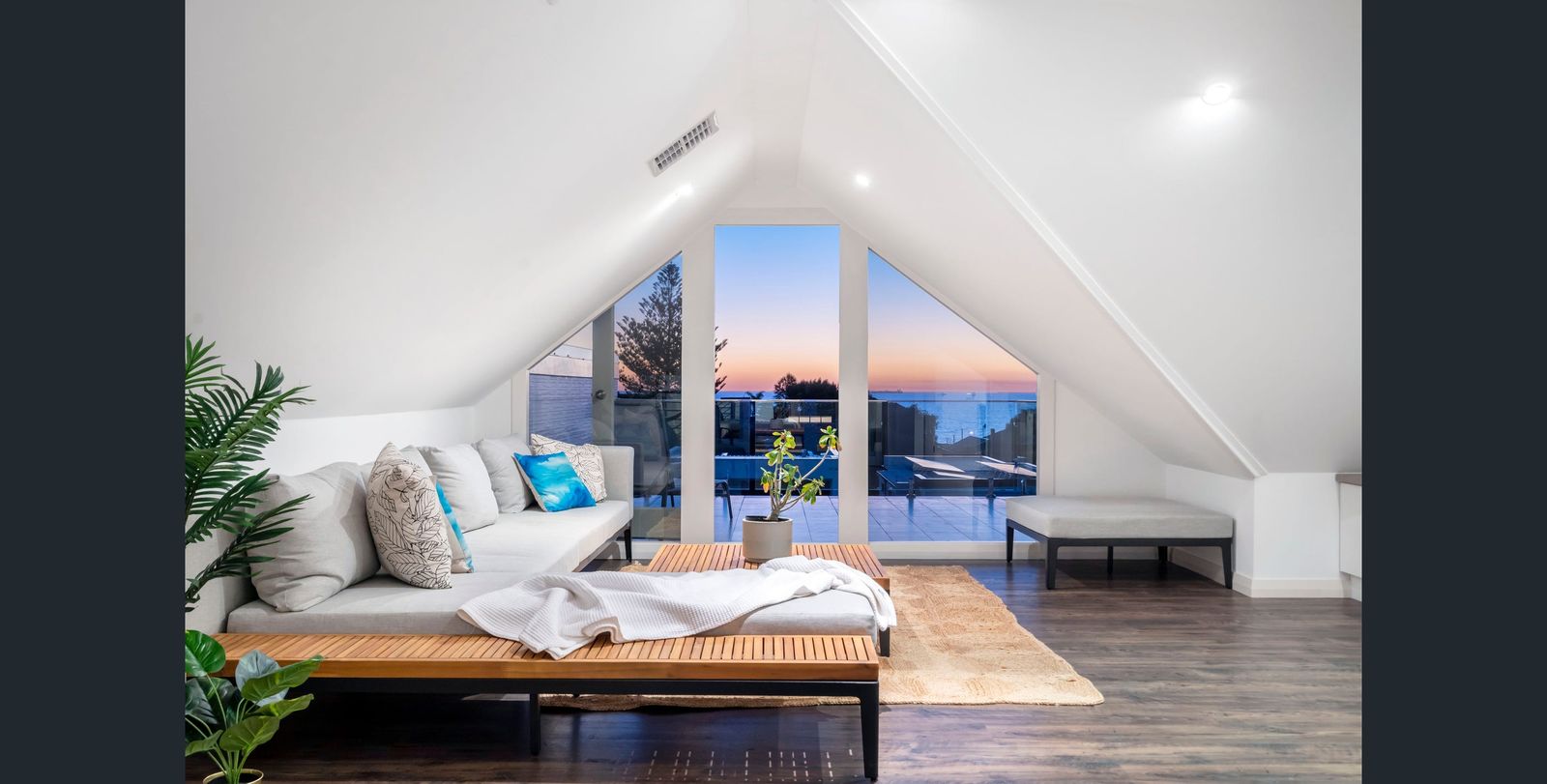 Upper-level lounge framing the ocean through triangular windows